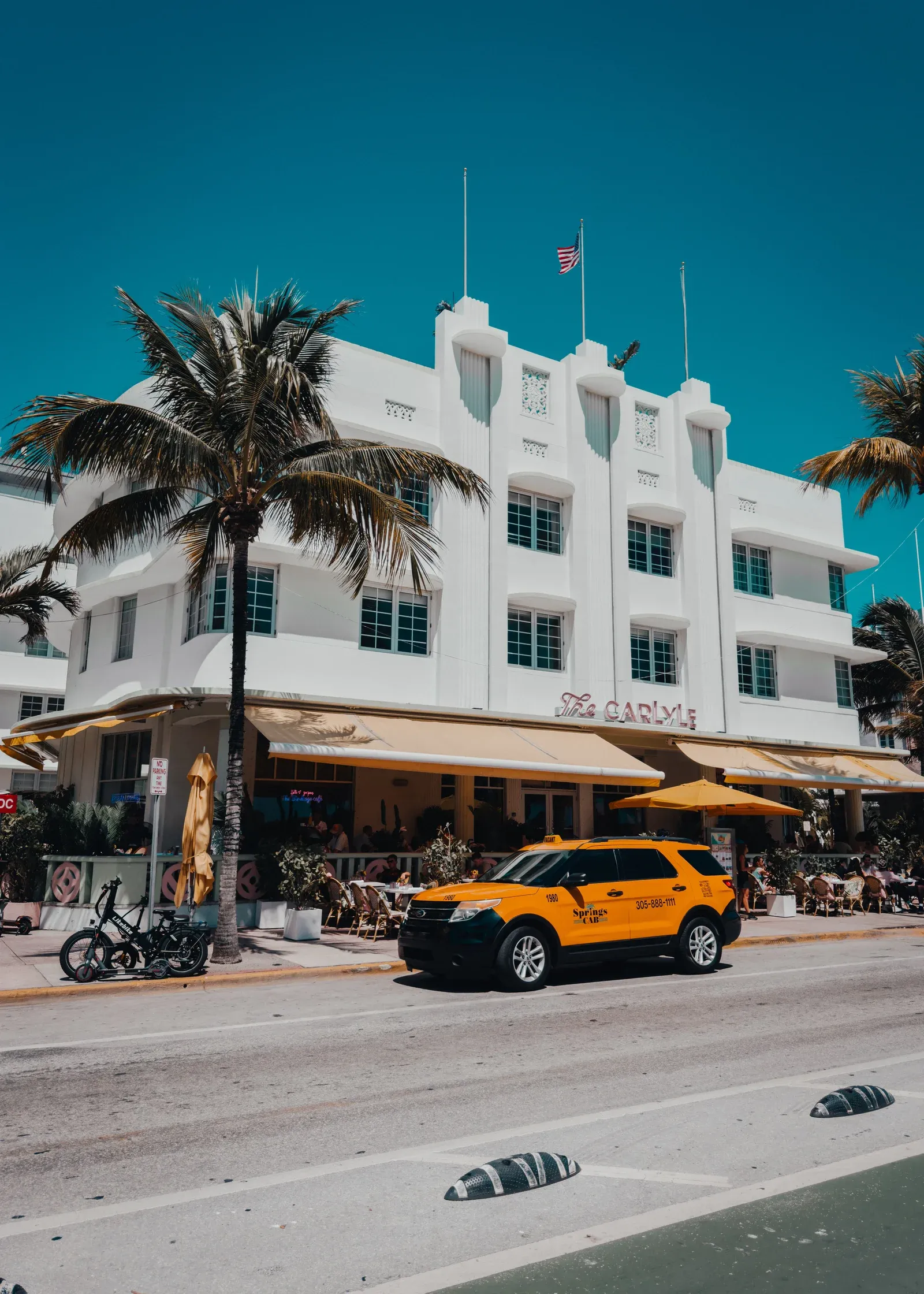The Carlyle hotel's white ziggurat-style Art Deco rooftop with flagpoles and stepped ornamentation on Ocean Drive in Miami Beach