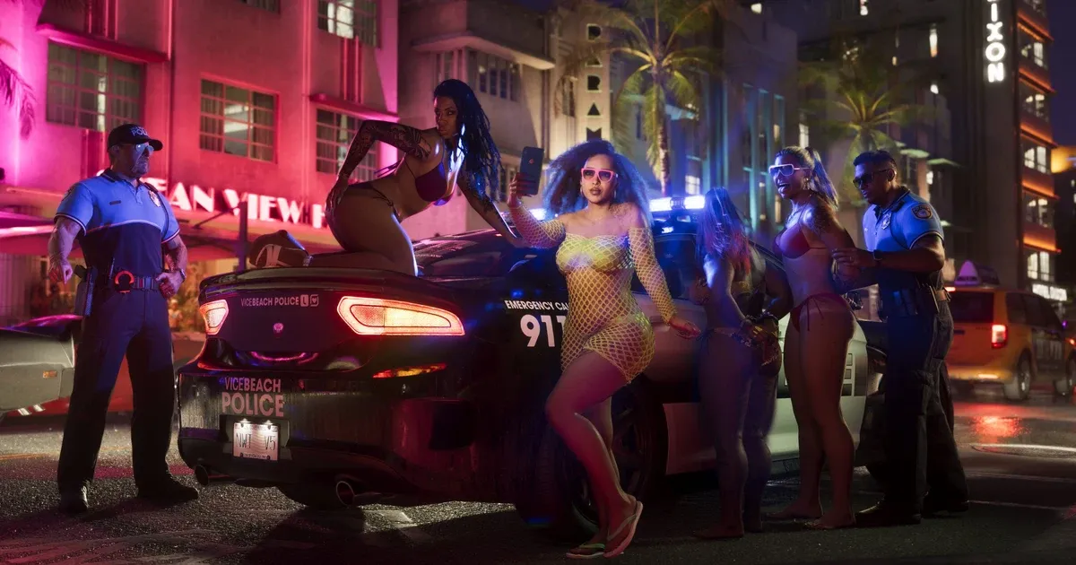 Pink and blue neon signs light up pastel Art Deco hotel facades along a palm-lined Vice Beach street at night in GTA 6, with police lights reflecting off the road